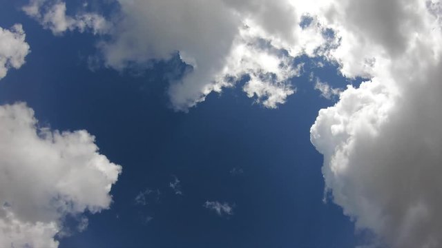 4K. Timelapse of clouds in a blue sky. The sun's rays pass through the clouds. Some clouds are dark-Adrian