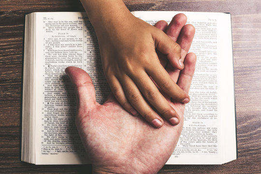 Child and Man Hands On The Bible
