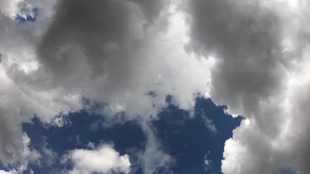 4K. Timelapse of clouds in a blue sky. The sun's rays pass through the clouds. Some clouds are dark-Adrian