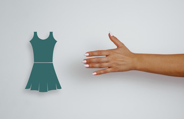 Top view of a woman's hand with pink tips reaches for a dress, clothes. The concept of purchases,...