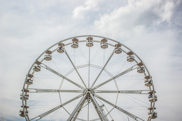 carnival entertainment concept of symmetry ferris wheel  construction object on cloudy gray sky...