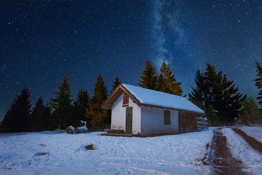 Beautiful winter house under the starry sky and milky way galaxy, abstract Christmas holiday background