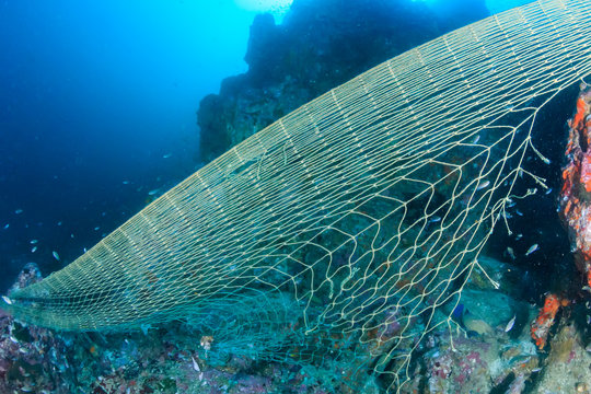 A large, discarded ghost fishing net entangled on a damaged tropical coral reef