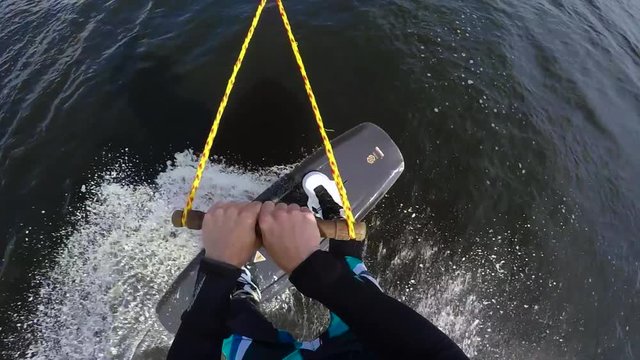 Sports guy in a wetsuit is riding a wakeboard on the river