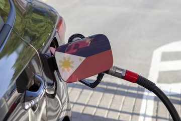 Fueling car with petrol pump at a gas station.