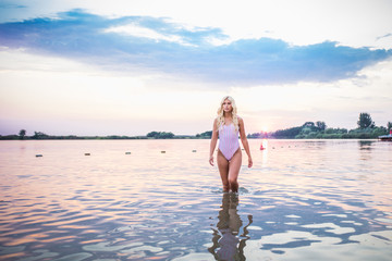 Attractive girl posing in water at sunset