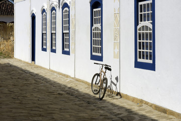 Fototapeta na wymiar Bicycle parked next to the white wall with blue windows
