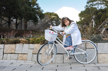 Beautiful girl, 7 years old (mixed race - Brazilian / Japanese) in their bicilcleta, looking fondly at his father and smiling without milk teeth.