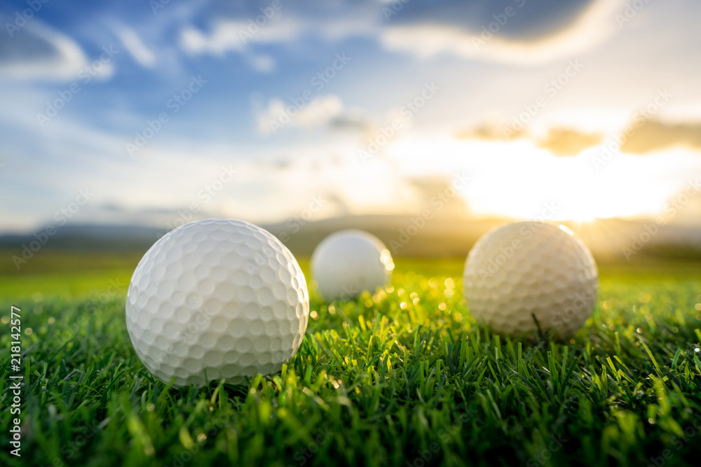 Wall mural close up the golf ball on the green background with sunset