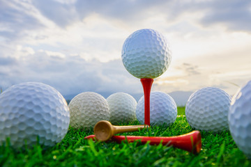 close up the golf ball on tee pegs ready to play and on green grass in the nature background