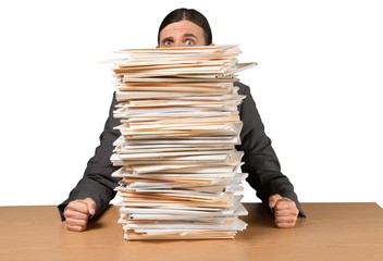 Young overworked manager at workplace with stacks of documents