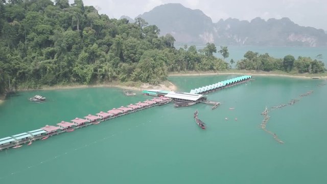 Aerial Drone panning footage over boat and lake house with beautiful aqua water color in khao sok national Park, Thailand, Surat Thani