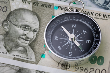 India financial and economy direction, new emerging market high growth country concept, closed up of compass on indian rupee banknotes on table