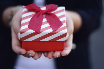 Female hands holding a gift box, present.