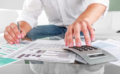 Close-up of a Person Analyzing Business Graphs with Calculator