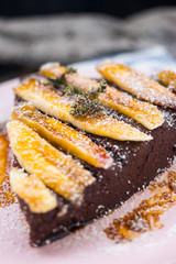 Vegan sweet cake. Raw chocolate pie. Vegetarian tart piece with bananas, maple syrup, dates, coconut and dark cocoa powder. Delicious and healthy breakfast or dessert.