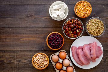 Healthy food. Products rich protein and fiber. Legumes, nuts, low-fat cheese, meet, eggs. Raw beans, chickpeas, lentil, almond, hazelnut on dark wooden background top view copy space