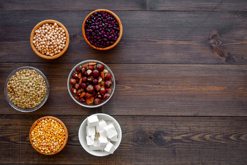 Vegan protein source. Legumes, nuts, cheese. Raw beans, chickpeas, lentil, almond, hazelnut on dark wooden background top view copy space