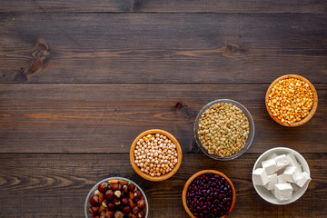 Vegan protein source. Legumes, nuts, cheese. Raw beans, chickpeas, lentil, almond, hazelnut on dark wooden background top view space for text