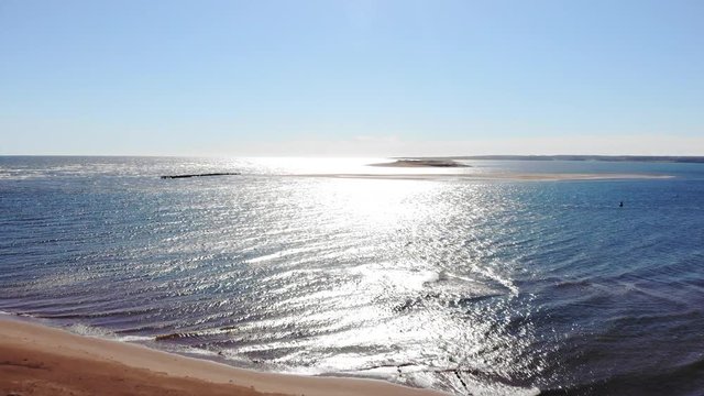 Beach front and tiny island across a water channel with peninsula in background
