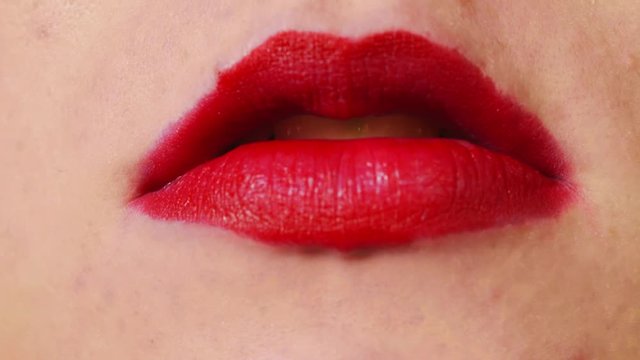 Woman with red lips smoking cigarette and blowing smoke, EXTREME CLOSE UP
