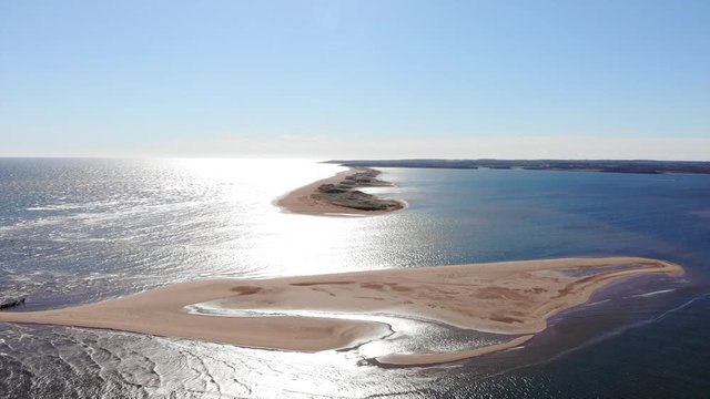 Small sandy island with broken pier and peninsula in the distance