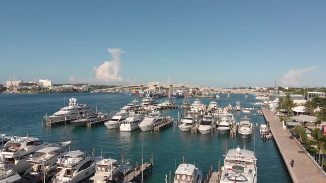 4K Cinematic Aerial flyover of yachts and boats in a marina right toward paradise island bridge.