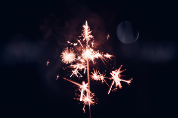 Hand holding burning Sparkler blast on a black background at night,holiday celebration event...