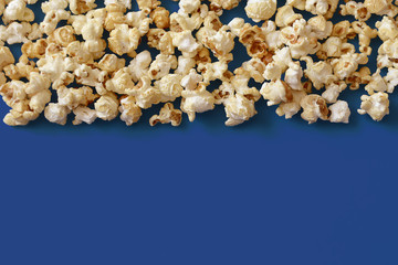 Popcorn, strewn with a strip on a blue background. View from above.
