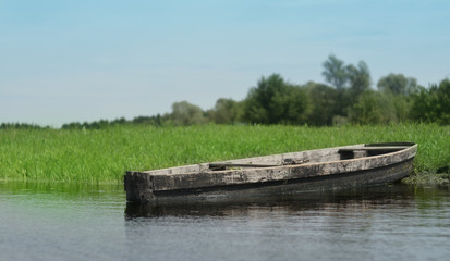 The old village wooden boat is moored at the river bank. Beautiful landscape.
