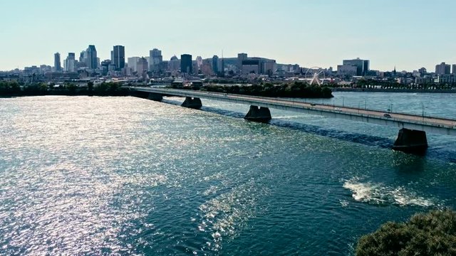 aerial drone footage of montreal with bridges and skyscrapers in the background on the horizon