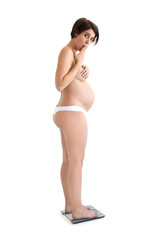 Schwangere Frau steht auf einer Waage und ist erstaunt über ihr Gewicht