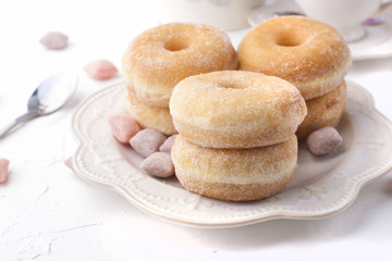 Donuts with sugar on a plate on a light background. Calorie Sweets for breakfast. Free place . Top view