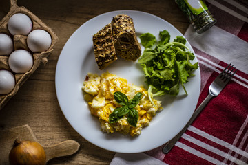 Easy breakfast - fried eggs with lettuce - in the background onion, fresh eggs and oak wood kitchen