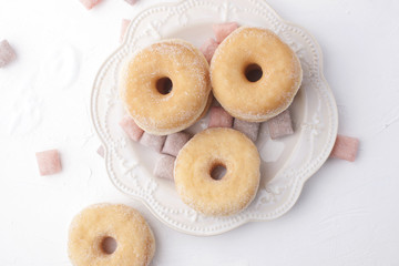 Donuts with sugar on a plate on a light background. Calorie Sweets for breakfast. Free place . Top view.