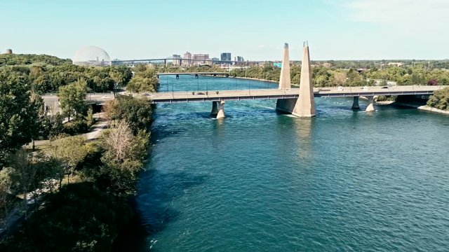 aerial drone footage of montreal with bridges and a park area plus ile sainte helene island with the biosphere dome in the background