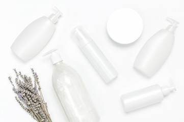 Cosmetic bottle containers with a bouquet of lavender on white background flat lay top view. Blank label for branding mock-up. Natural beauty product concept. Shower gel, shampoo, liquid soap