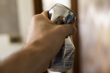 Mano che impugna lattina in alluminio schiacciata © Antonio