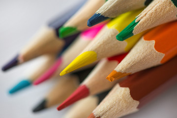 Pile of sharp coloured drawing pencils on table. Rainbow colors  red, yellow, blue, green, purple. Concept of art, crafts and kids having fun