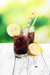Softdrink with ice cubes, lemon and straw in glass