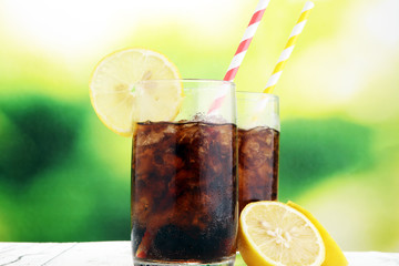 Softdrink with ice cubes, lemon and straw in glass