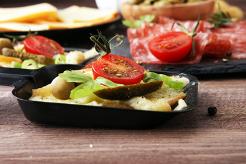 Delicious traditional Swiss melted raclette cheese on diced boiled or baked potato served in individual skillets with salami..