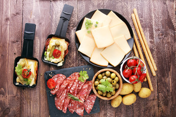 Delicious traditional Swiss melted raclette cheese on diced boiled or baked potato served in...