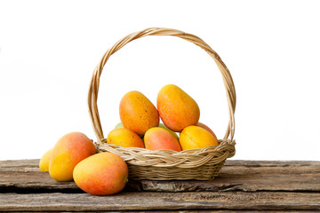 Mango tropical fruit in basket on wood desk isolated white background