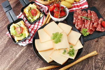Delicious traditional Swiss melted raclette cheese on diced boiled or baked potato served in individual skillets with salami..