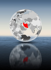 Iran on translucent globe above water