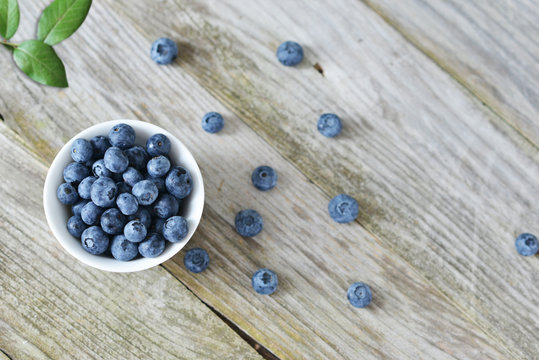 Fresh blueberries from ecological agriculture in white bowl on wooden or rustic background
