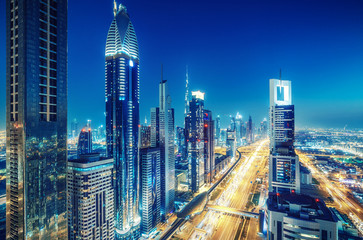 Colorful skyline of a big modern city with illuminated skyscrapers and highways. Aerial view over downtown Dubai, UAE. Travel and architectural background.