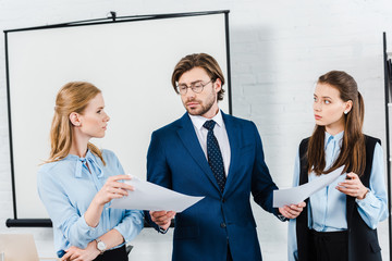 young businesswomen showing papers to their boss at modern office