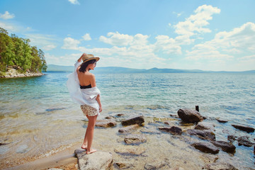 beautiful slender girl relaxing on the rocky beach of a large la